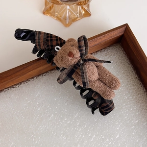 Détail de la texture en tissu écossais marron et de l'ours en peluche sur la pince à cheveux