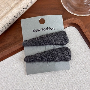 Close-up of black knitted wool hair clips on display card with warm vintage decor