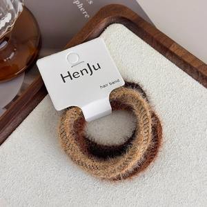 Close-up of two plush faux fur hair ties in coffee and camel brown on display card