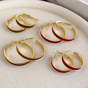 Retro red and brown velvet gold hoop earrings in two sizes shown on an elegant tray