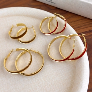 Detail view of four sets of gold hoop earrings with dark red velvet and brown enamel inlay