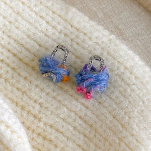 Vue détaillée des boucles d'oreilles sac en laine arc-en-ciel sur tricot douillet