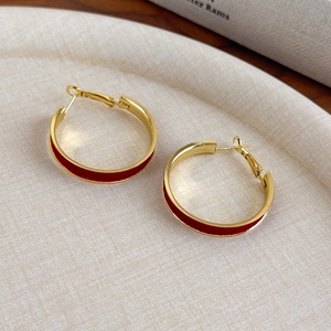 Detail view of large gold hoop earrings featuring elegant red velvet texture inlay