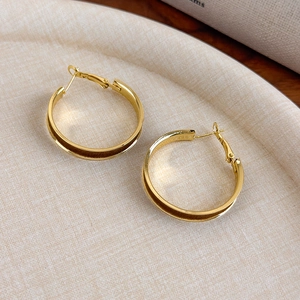 Close-up of gold circle earrings with brown velvet inlay on a textured beige tray