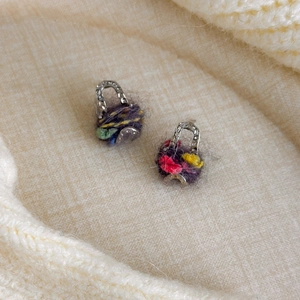Détails macro de boucles d'oreilles sac en laine sur texture tricotée beige