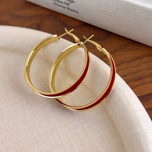 Detailed macro shot of large red velvet hoop earrings with elegant golden metal finish