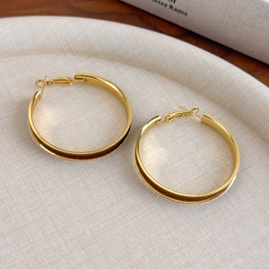 Detail of elegant gold hoop earrings with red velvet texture and grooved pattern design