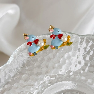 Cute enamel rabbit earrings with pearl and rhinestone accents on a glass background