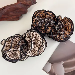 Close-up of ruffled leopard print fabric hair scrunchie with elegant black stitched edges