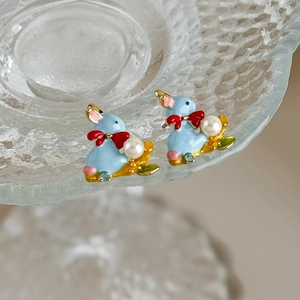 Close-up of enamel rabbit earrings with white pearls and tiny blue rhinestones details