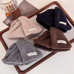 Winter knitted wool beanies in four colors with beige logo patch in a wooden tray
