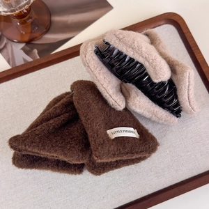 Detailed view of large brown and beige wool fabric hair claws on a wooden tray