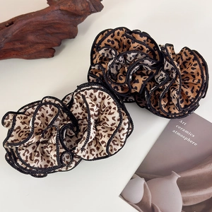 Detailed macro view of leopard print hair scrunchies with elegant black rolled edge finish