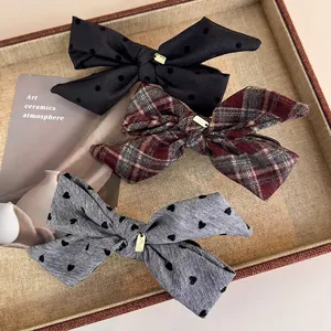 Three bow hair clips set with polka dots and plaid patterns in a woven basket