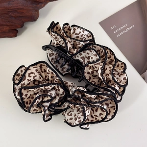 Detailed close-up of leopard print chiffon hair clip with pleated edges and black plastic teeth