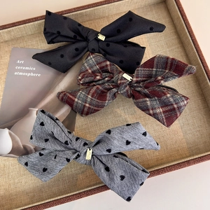 Three fabric bow hair clips featuring polka dots, plaid, and heart patterns with gold tags