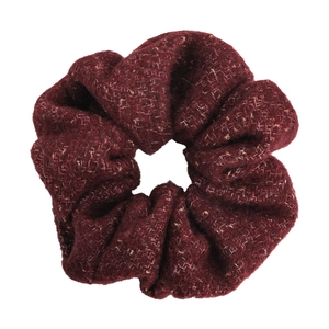 Chouchou en tweed bordeaux avec fil pailleté doré sur un fond blanc minimaliste