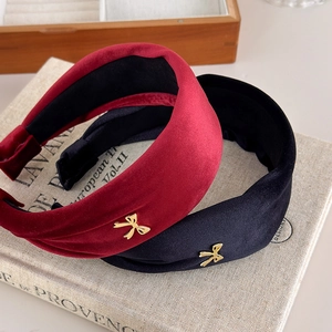 Detailed view of red and black velvet headbands with elegant gold bow accents