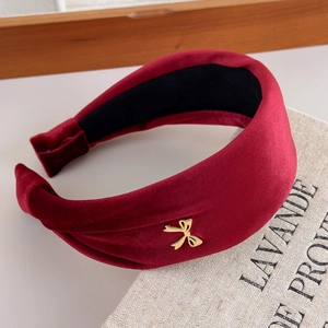Detail of red velvet headband with golden bow charm on vintage book background