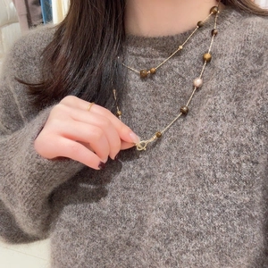 Macro shot of tiger eye stone necklace with OT toggle clasp on a fuzzy sweater