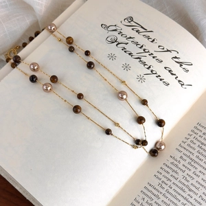 Close-up of double-layer tiger eye stone and pearl necklace on an open book page