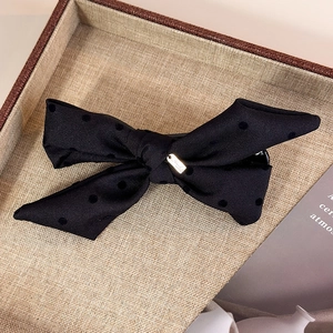 Detail of black polka dot bow hair clip with luxury gold metal plate and velvet texture