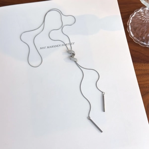 Detail du collier long en Y argenté avec noeud en cristal et pendentifs barres