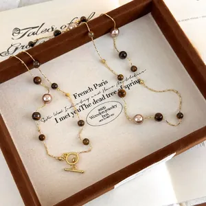 Macro detail of tiger eye stone and pearl necklace with golden OT buckle on vintage display