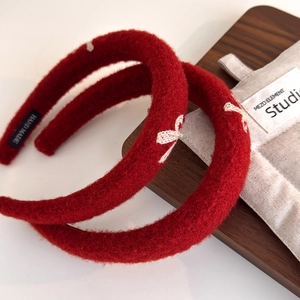 Plush red New Year headband with embroidered bow and handmade label on wooden tray