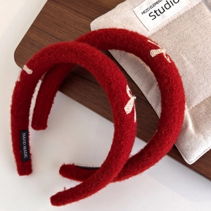 Detail of red plush headbands with beige bow embroidery and handmade woven labels