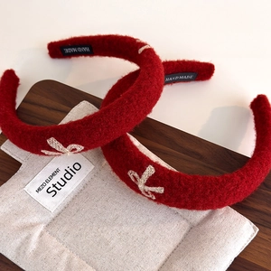 Handmade red plush headband with white embroidered bow and thick padded velvet texture