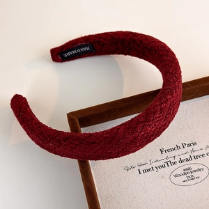 Deep red woven wide headband with handmade texture displayed on a wooden jewelry tray