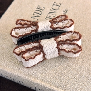 Detail view of knitted double bow hair clip with brown wave edges and non-slip design