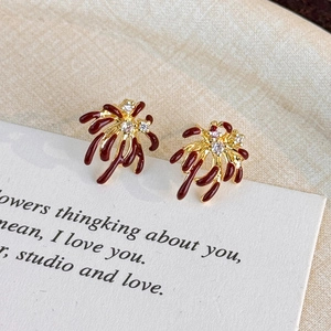 Detailed macro of red fireworks zircon earrings with gold plating and crimson enamel finish
