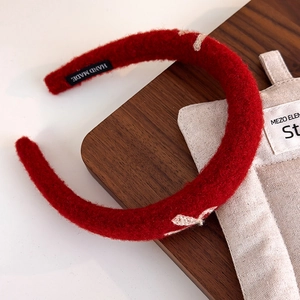 Close-up of a red plush headband with white embroidery and a handmade woven label