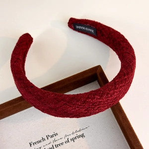 Detail of burgundy wool knit headband with handmade label and retro woven texture
