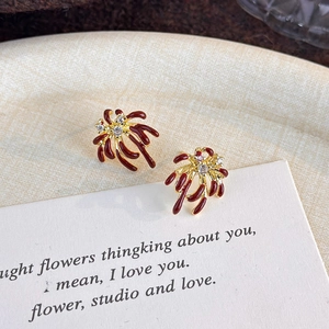 Macro shot of red firework zircon earrings with gold plating on beige textured fabric