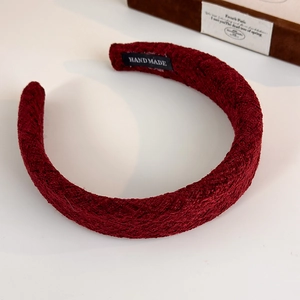 Close-up of handmade dark red woolen wide headband with detailed woven texture on gift box