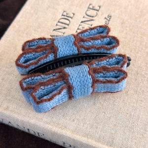 Detail of vintage knit bow hair clip with navy fabric and brown stitched edges