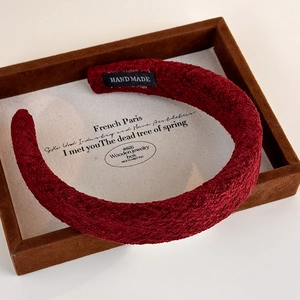 Detail view of burgundy knitted headband featuring textured patterns and hand made label