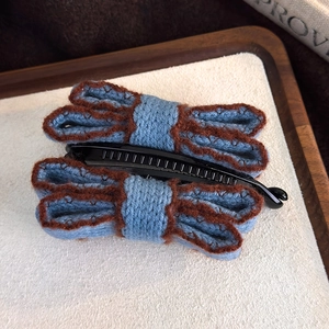Close-up of vintage blue knitted double bow banana hair clip with plush texture detail