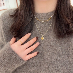 Collier double rang doré avec pendentif oeil de tigre sur un pull marron chic