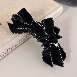 Close-up of elegant velvet bow hair clip with white stitching on a vintage book