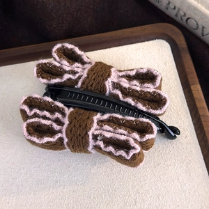 Detail of a brown knitted bow banana hair clip with pink wave stitching and comb teeth
