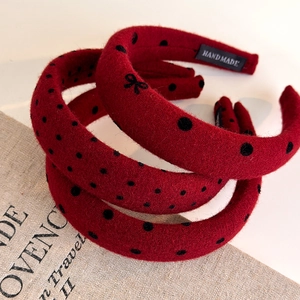 Close-up of a red polka dot headband with a black bow and a Hand Made label detail