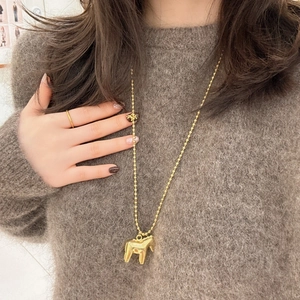 Golden bead chain necklace with Dala horse pendant worn on a brown mohair sweater