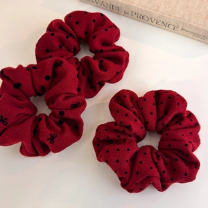 Detailed close-up of dark red polka dot scrunchies with black bow embroidery
