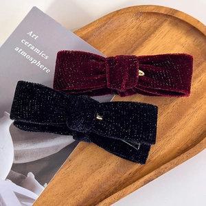 Sparkly velvet bow banana hair clips in black and wine red colors on a tray