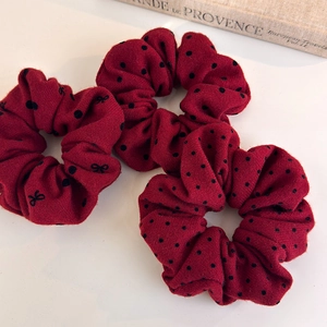 Detail view of three retro red polka dot scrunchies with bow patterns on white background