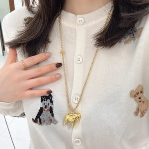 Close-up of golden bead chain necklace with a 3D trojan horse pendant on a white sweater